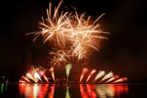Golden fireworks reflected in water during a night festival